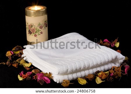 towel candle and dried flowers on black background
