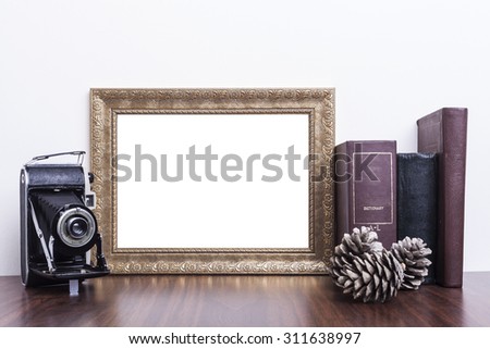 Golden Frame with old books and old camera on wood table
