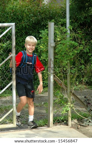 Boy walking through gate, arriving home from school
