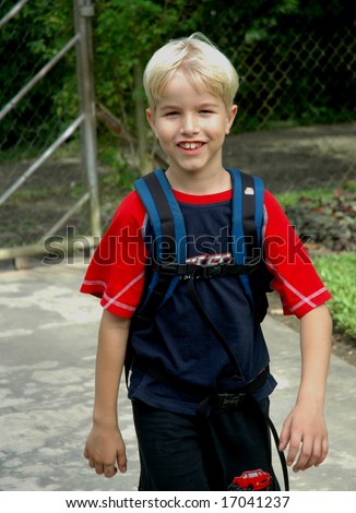 Boy arriving home from school, smiling as he walks up the driveway