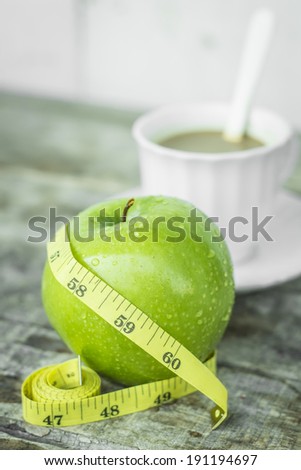 Green apple with waist and measuring tape and Drinking coffee make fat