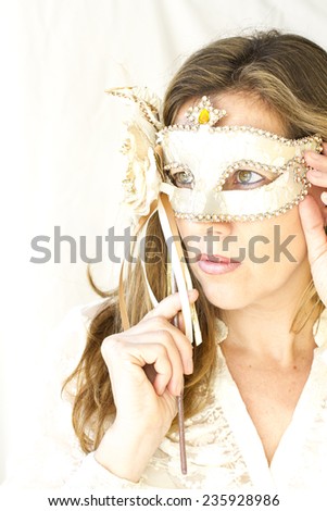 portrait of attractive caucasian woman holding a beautiful Venetian mask, photography in high key, very soft and elegant pose tones.
