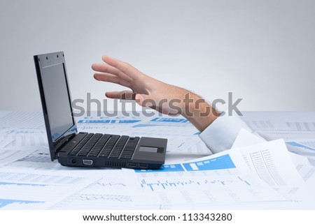 Drowning in paperwork concept. White collar worker reaching out after computer - rescue of paperwork.