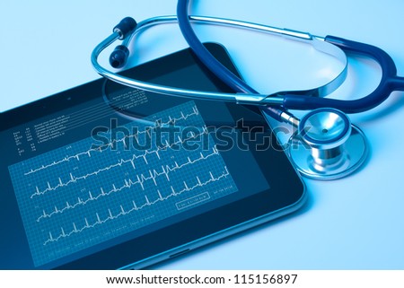 Doctor workplace with digital tablet and stethoscope. Electrocardiogram (ECG) on tablet screen. Application of modern technology in medicine concept.