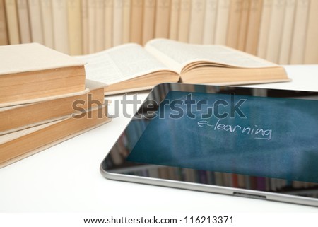 E-learning concept. Digital tablet in study room with image of chalk board on touch screen with handwritten text e-learning.
