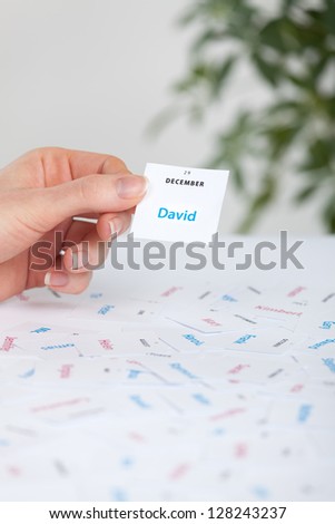 Woman select first name for child (David). First names printed on paper and date of name day.