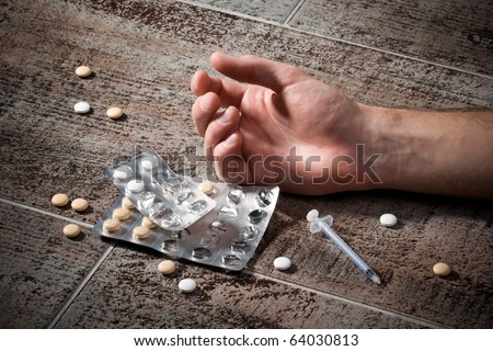 Drug overdose concept - hand on floor, pills and injection