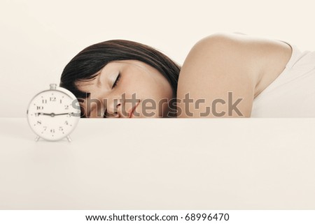 Sleeping long woman with alarm clock. Focused on face. Auburn tint.