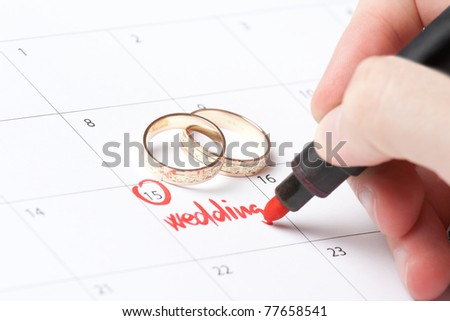 Wedding rings and hand writing word wedding into calendar