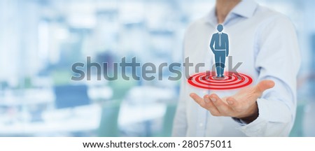 Target customer (marketing) concept. Businessman hold target customer represented by virtual icon of man standing on target. Wide banner composition, office in background.