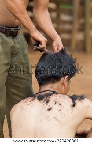 XEKONG, LAOS, APRIL 13 : An unidentified man haircut with clipper at ground in the village of Xekong, Laos, on April 13, 2014