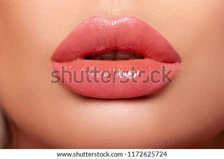 Close-up Beautiful lips. Part of face, young woman close up. Sexy plump lips Nude lipstick. peach color of lipstick on large lips