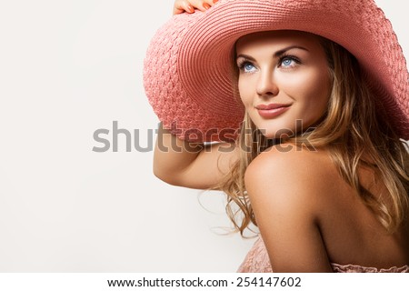 Beautiful girl . A tanned slim girl in a hat with a light-up. Cute woman in a peach hat on her head,her face a gentle make-up and a beautiful smile.Portrait of a girl in the hat on a light background