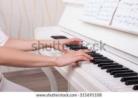Beautiful hands on the white keys of the piano playing a melody. Women\'s hands on the keyboard of the piano, playing the notes melody.Hands of a young girl in the interior, it plays music on the piano