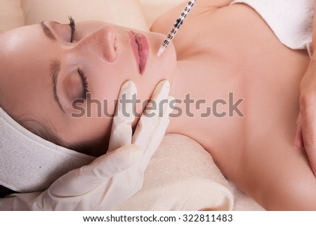 Beauty injections.a woman and a syringe.Elegant woman on beauty treatments in the spa salon,smooth clean skin on her face,her doing  beauty prick.A woman lying on her back with closed eyes.Cosmetology