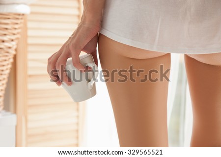 A woman and a bedroom.Girl standing at the open window close up back in her hands with coffee.Photo of female priests and cup of coffee close-up of woman standing at the window in which the sun shines