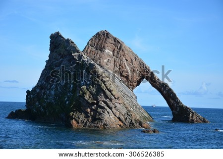 This is Bow Fiddle Rock at Portknockie, Moray, Scotland.  In the gap between the two sections of rock we can see a fishing boat.