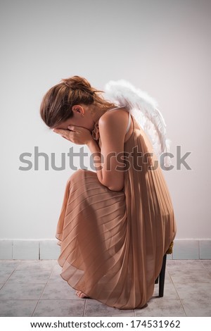 Lonely angel sitting on the chair and crying.