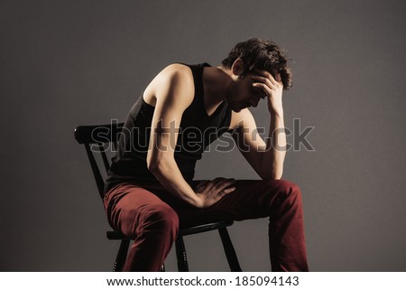 A young man sitting alone in confusion