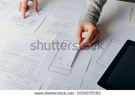 Web designer creating mobile responsive website. Website wireframe sketches on white table