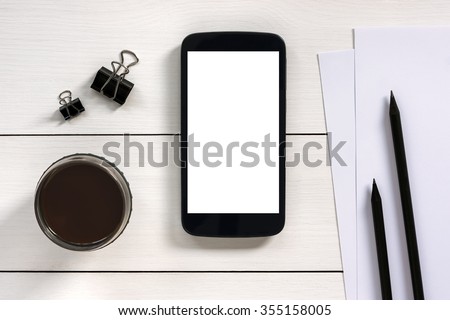 Smart phone mock up with office objects on white wooden table. View from above.