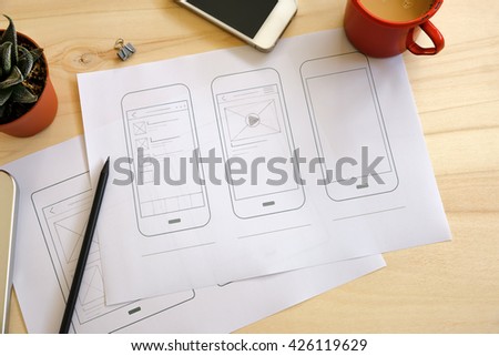 Designer desk with UI wireframe sketches. View from above