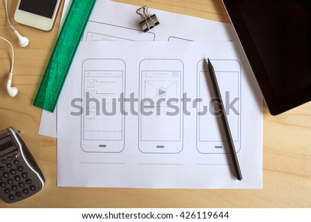 Designer desk with paper prototype of a mobile application. Flat lay.