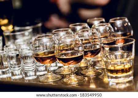 Various alcohol drinks standing on bar in snifters and shot glasses