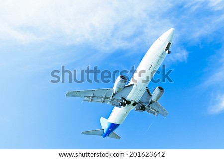 Landing plane on blue sky. Descending jet with landing gear. The view from below