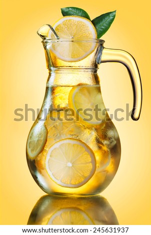 Misted lemonade pitcher with lemon slices and ice cubes decorated with leaves on yellow.  Mixed drink from iced tea and lemonade (also known as \