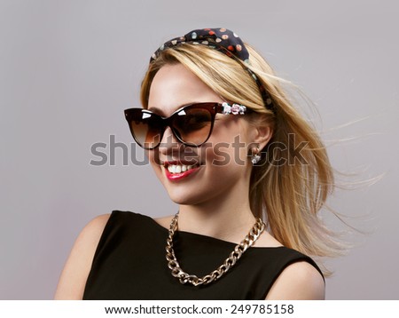 Cheerful glamorous young lady with streaming hairs on plain background. Portrait of smiling woman wearing sunglasses
