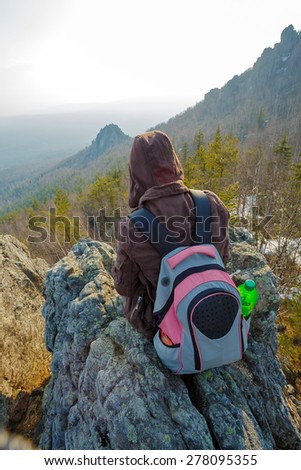 Adventurous female hiker sitting on the rock.  Wide angle perspective. Tourism, adventure, hiking concept.