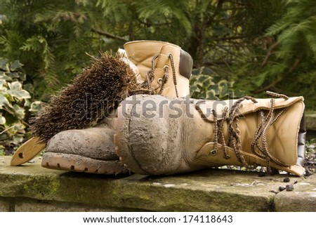 Pair of dirty work boots waiting to be cleaned. One is lying on its side.