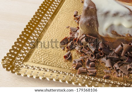 close up view of a three chocolate cake with chocolate chips over a golden tray