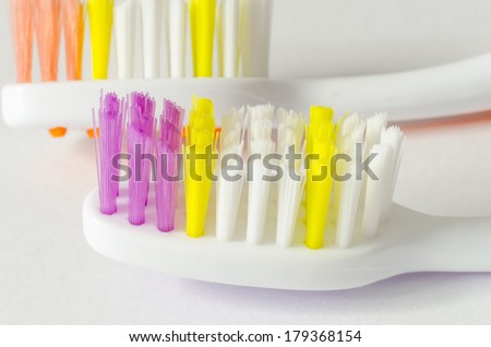 Two toothbrush heads with bristles in orange, violet, white and yellow. Dentistry and health objects