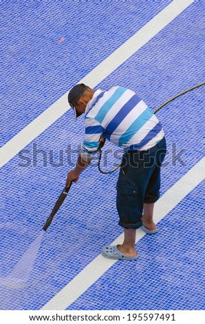 A worker cleaning the pool ground with a pressure pump