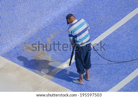 A man is cleaning the pool ground with a pressure pump
