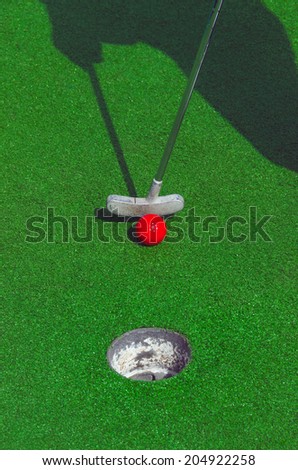 Somebody is playing minigolf with a red ball. Mini golf recreation