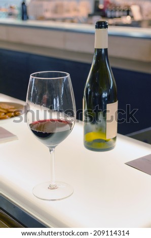 A cup of red wine near an empty bottle