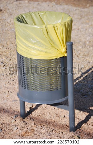Urban trash can with a yellow bag. Street furniture