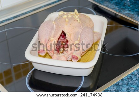 whole raw chicken on a tray ready to be roasted with garlic, oil, honey and lemon