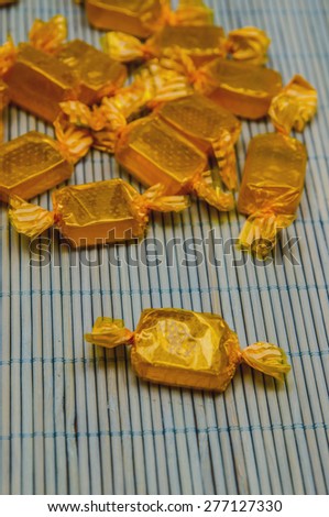 Yellow candies wrapped in plastic foils over a bamboo tablecloth