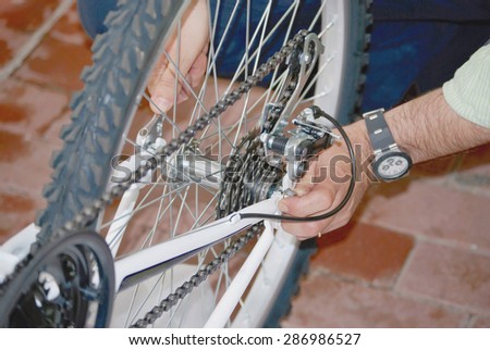 Bike repair. A man repairs the wheel of a bicycle with the hands and one adjustable spanner.