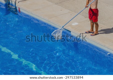 A man is cleaning the swimming pool. Summer maintenance service