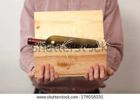 Closeup shot of man in shirt showing wine in wooden box