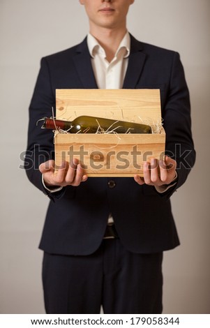 Portrait of elegant man in suit holding wooden box with wine