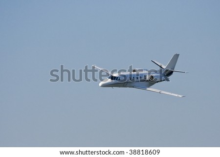 Small private jet landing or taking off with background of blue sky