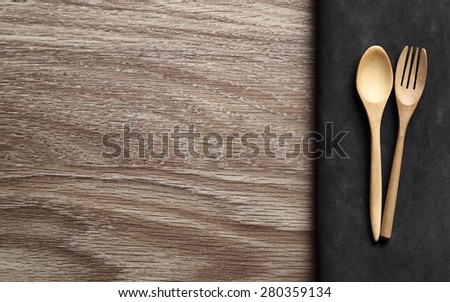 Wooden Spoon and Fork on Cloth color black and wood Table. Menu Set Concept