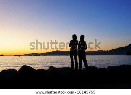 The couple are facing beautiful sunset in English Bay, Vancouver