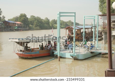 Ayutthaya, Thailand - November 23rd, 2014: Small ferry unloading motorcycle onto small pier on 23/11/2014 in Ayutthaya province. The sign above ferry state maximum capacity is 12 people.